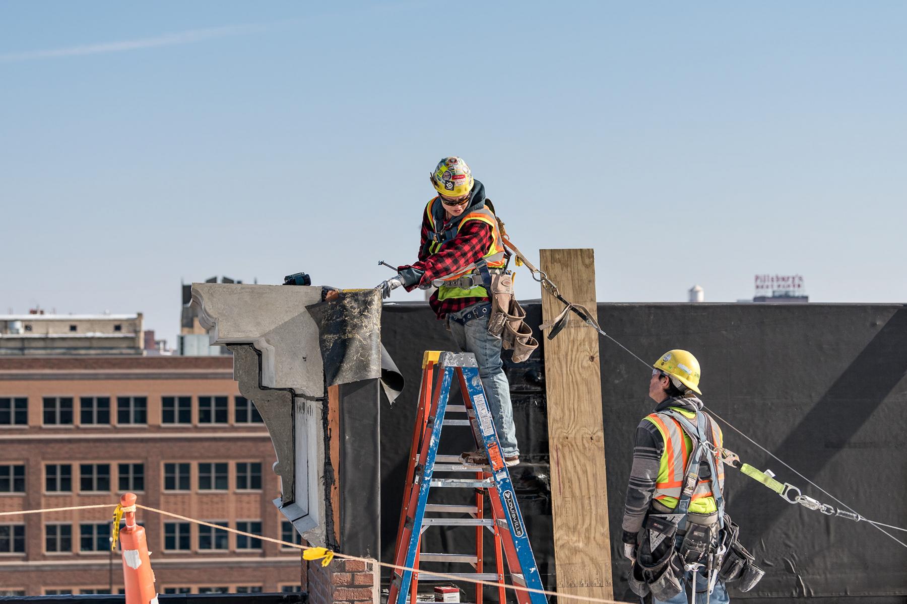 A craft worker is on a ladder working at a project site. 