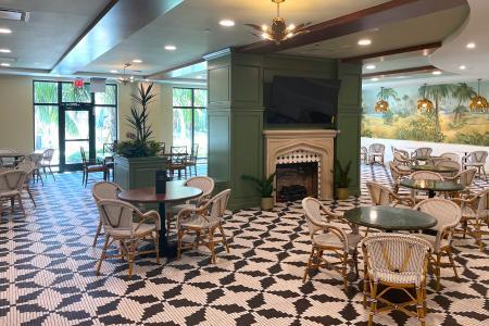 A view of one of the dining areas at  Living at Wellen park featuring stylish bistro dining tables, hand-laid tiles and tropical mural.